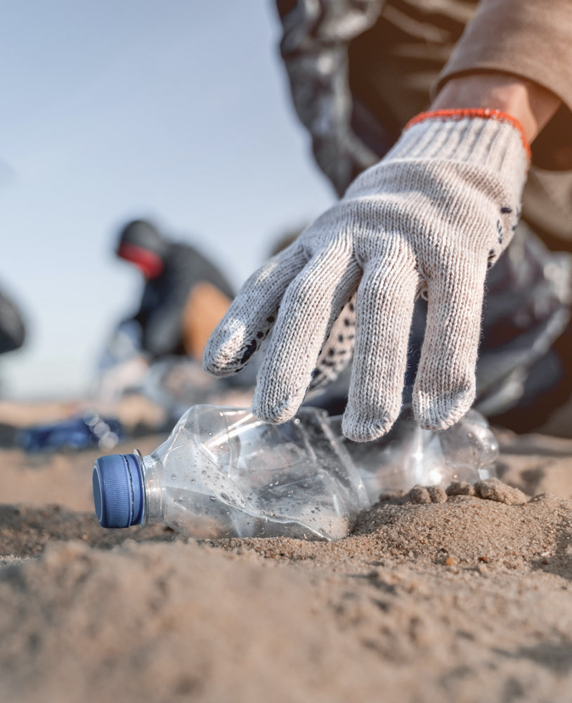 gloved hand cleaning up beach